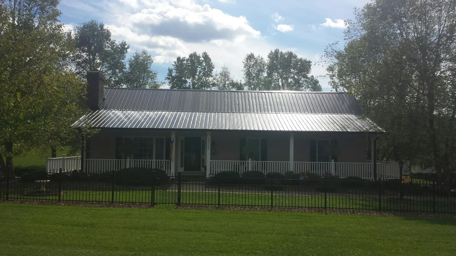 Gray metal roof on a brick ranch with a full width front porch — Gutter Guard Installation work by our crew in Philadelphia