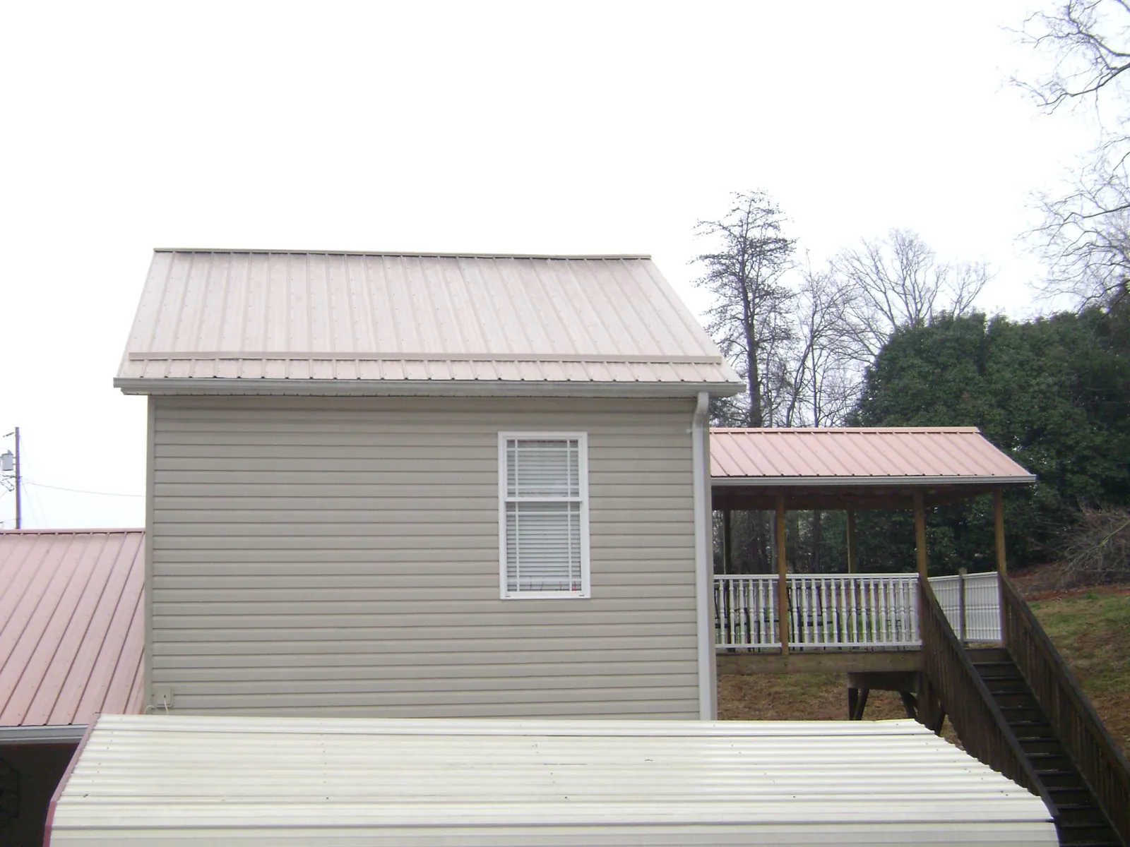 Tan metal roofs on a two story addition and attached porch, from a Roof Replacement job in Philadelphia
